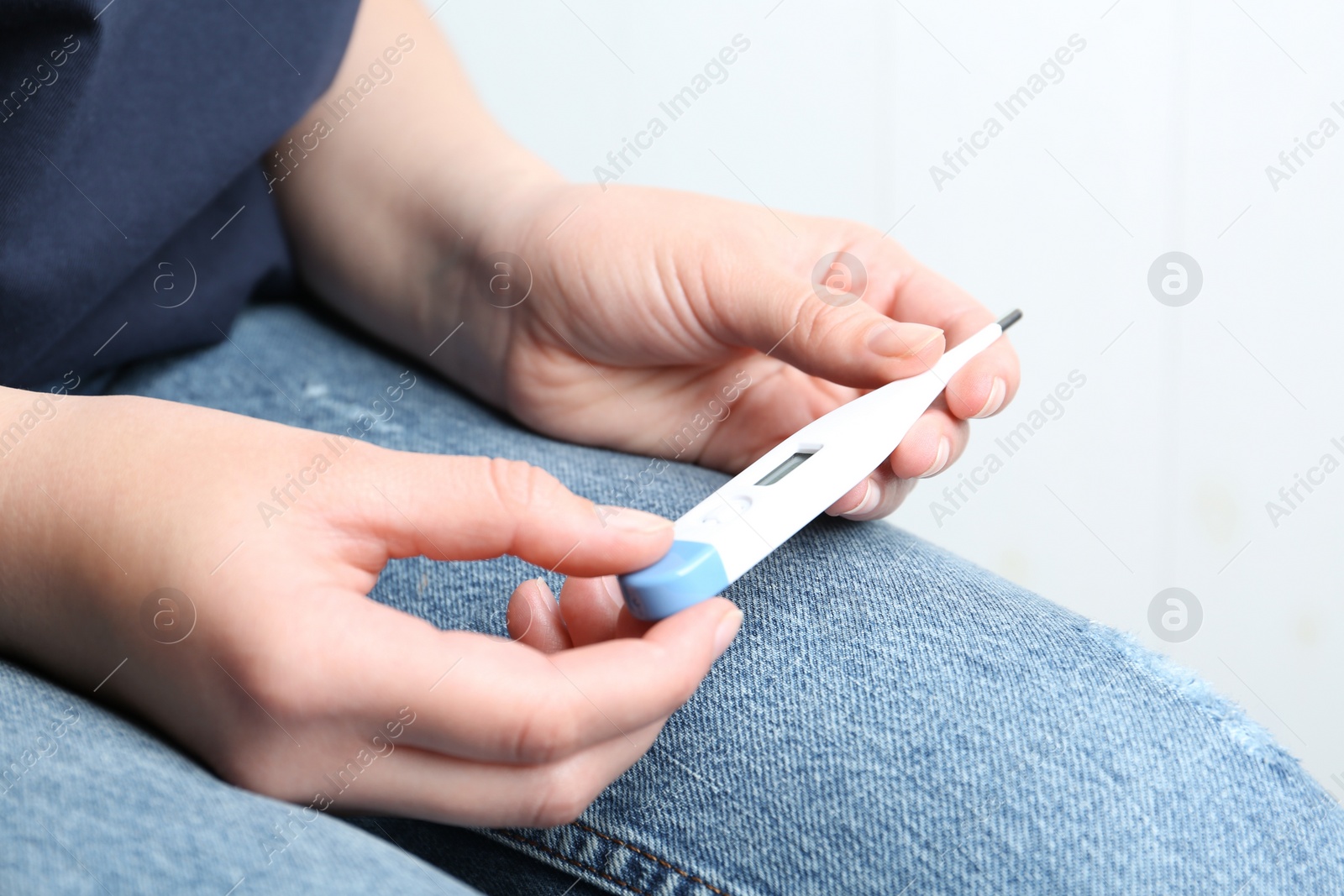 Photo of Woman with digital thermometer on light background, closeup