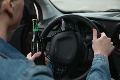 Man with bottle of beer driving car, closeup. Don't drink and drive concept