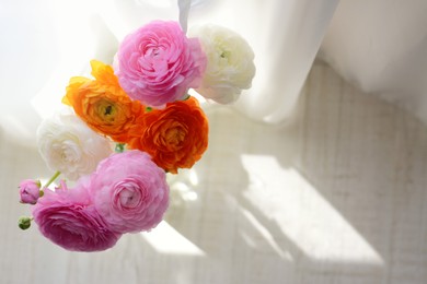 Photo of Bouquet of beautiful ranunculus flowers near window on floor, top view. Space for text