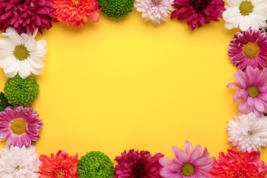 Photo of Frame made of beautiful chrysanthemum flowers on yellow background, flat lay. Space for text