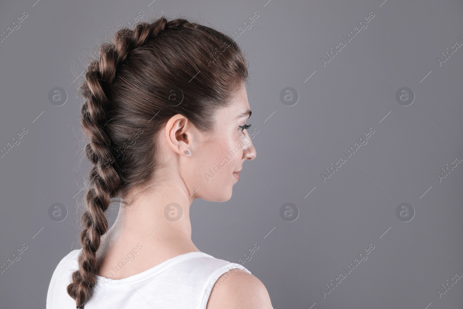 Photo of Woman with braided hair on grey background. Space for text