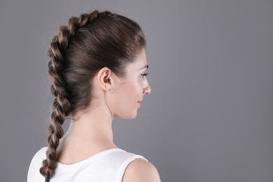 Woman with braided hair on grey background. Space for text