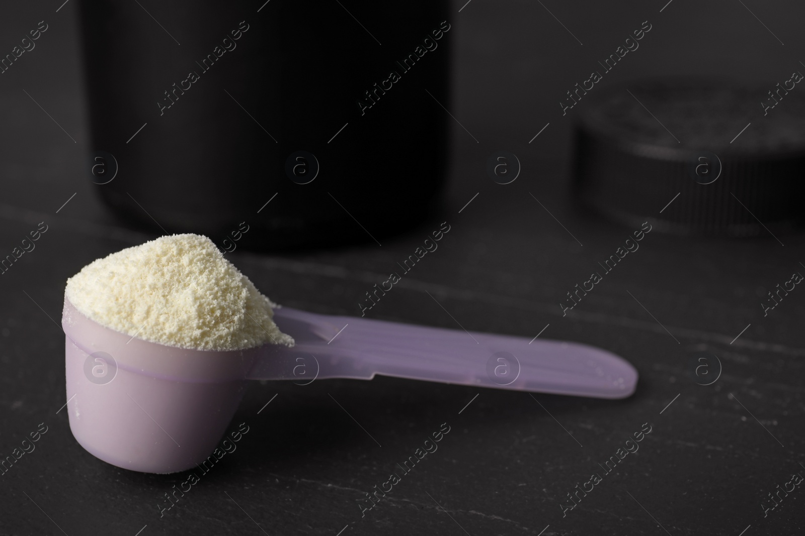 Photo of Scoop of protein powder on black table