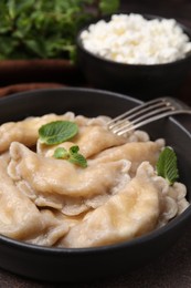 Photo of Delicious dumplings (varenyky) with cottage cheese and mint served on table, closeup