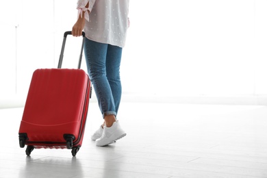 Woman with red travel suitcase in airport. Space for text