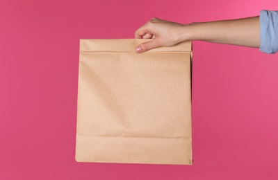 Woman holding paper bag on color background. Mockup for design