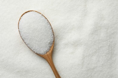 Wooden spoon on granulated sugar, top view