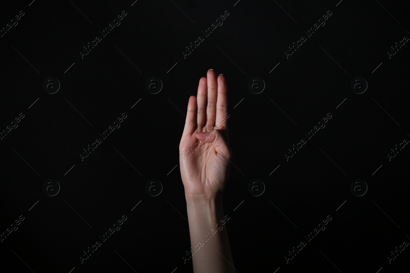 Photo of Woman showing open palm on black background, closeup