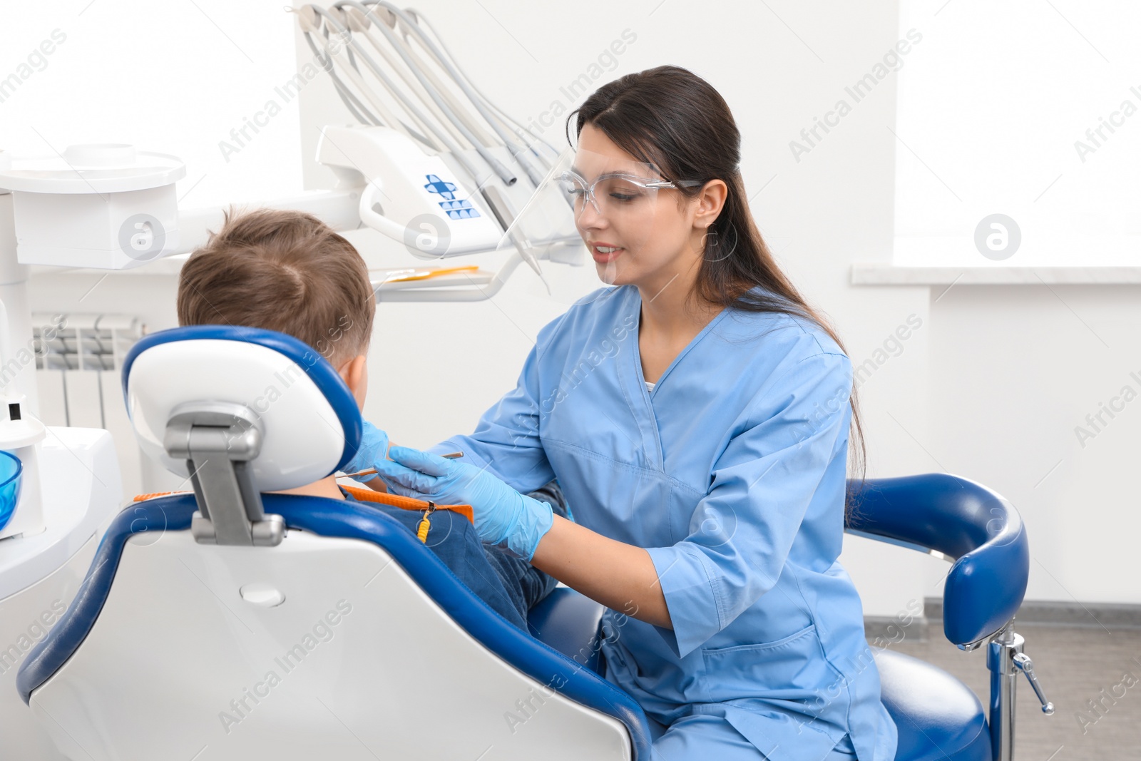 Photo of Professional dentist working with little boy in clinic