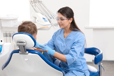 Photo of Professional dentist working with little boy in clinic