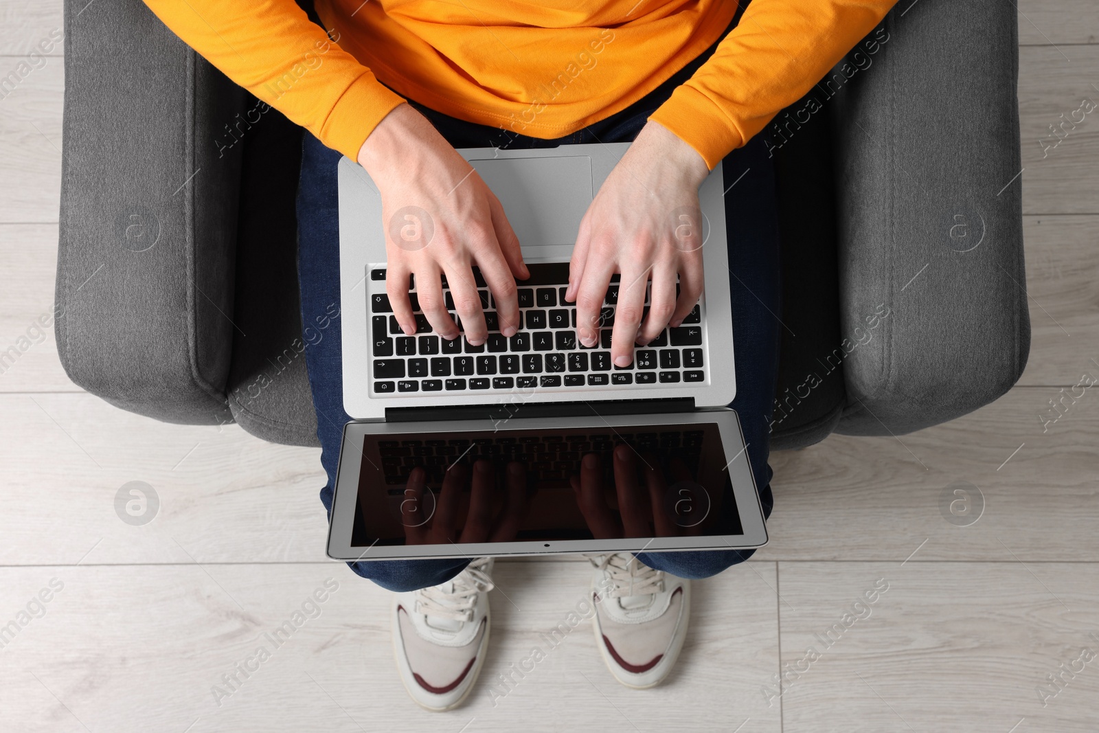 Photo of Man working with laptop in armchair, top view