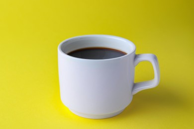 Photo of White mug of freshly brewed hot coffee on yellow background