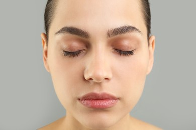 Photo of Young woman with perfect eyebrows on grey background