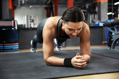 Young woman doing plank exercise in modern gym