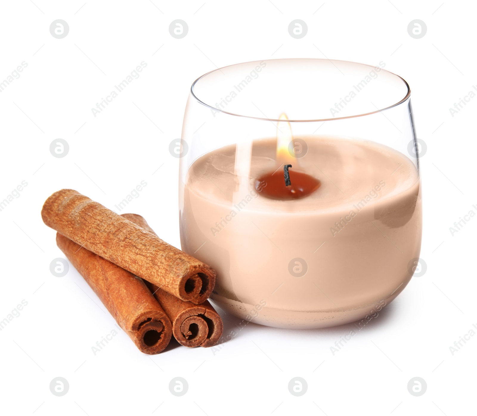 Photo of Color wax candle in glass holder and cinnamon sticks isolated on white