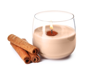 Photo of Color wax candle in glass holder and cinnamon sticks isolated on white