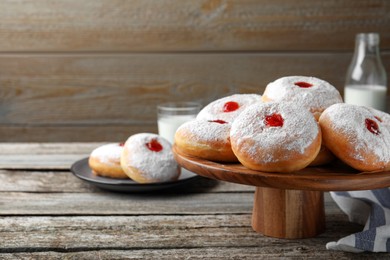 Pastry stand with delicious jelly donuts on wooden table. Space for text