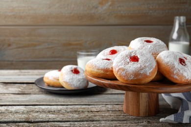 Photo of Pastry stand with delicious jelly donuts on wooden table. Space for text