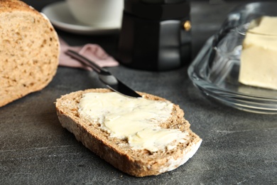 Slice of tasty bread with butter on dark table