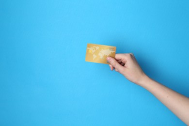 Photo of Woman holding credit card on light blue background, closeup. Space for text