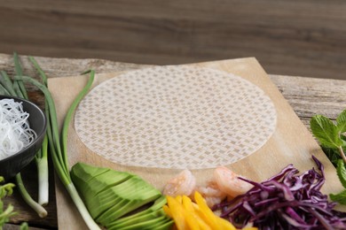 Photo of Rice paper and other ingredients for spring rolls on wooden table