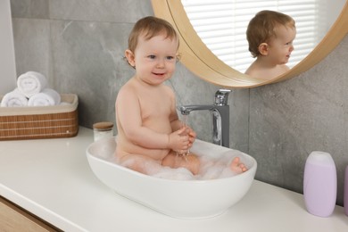 Cute little baby bathing in sink at home