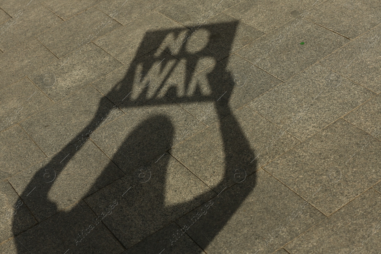 Photo of Shadow of woman holding poster with words No War outdoors