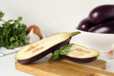 Photo of Cut eggplant and basil on white table