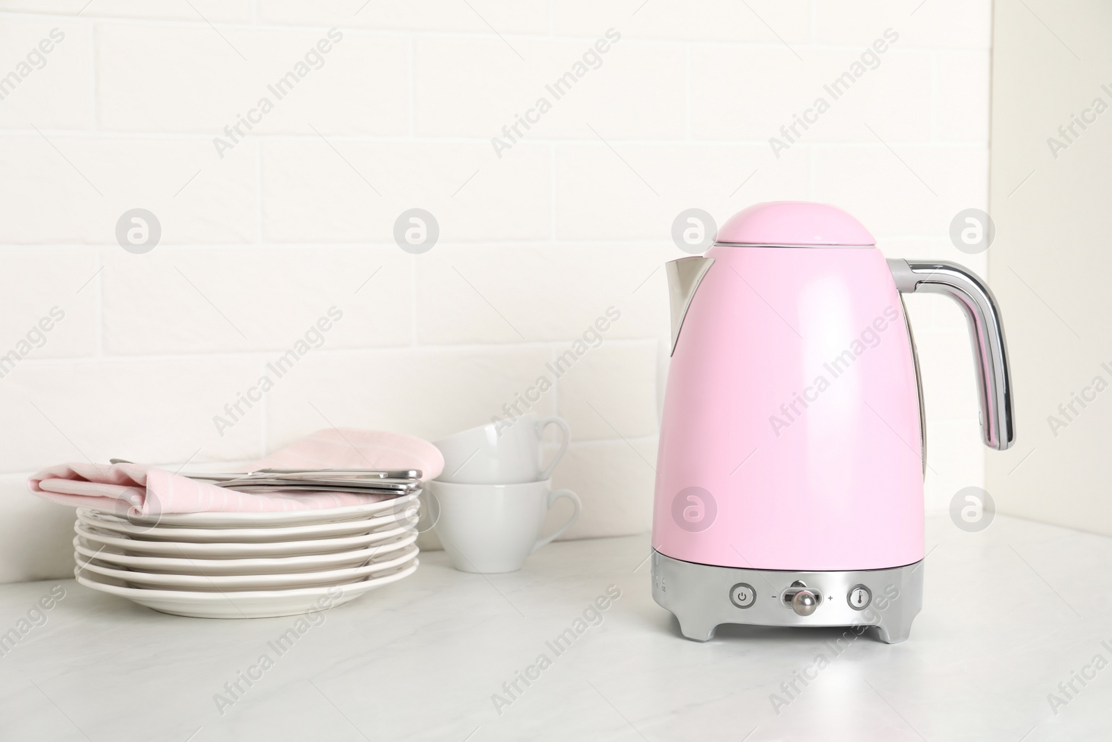 Photo of Modern electric kettle and dishes on counter in kitchen