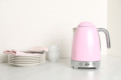 Photo of Modern electric kettle and dishes on counter in kitchen