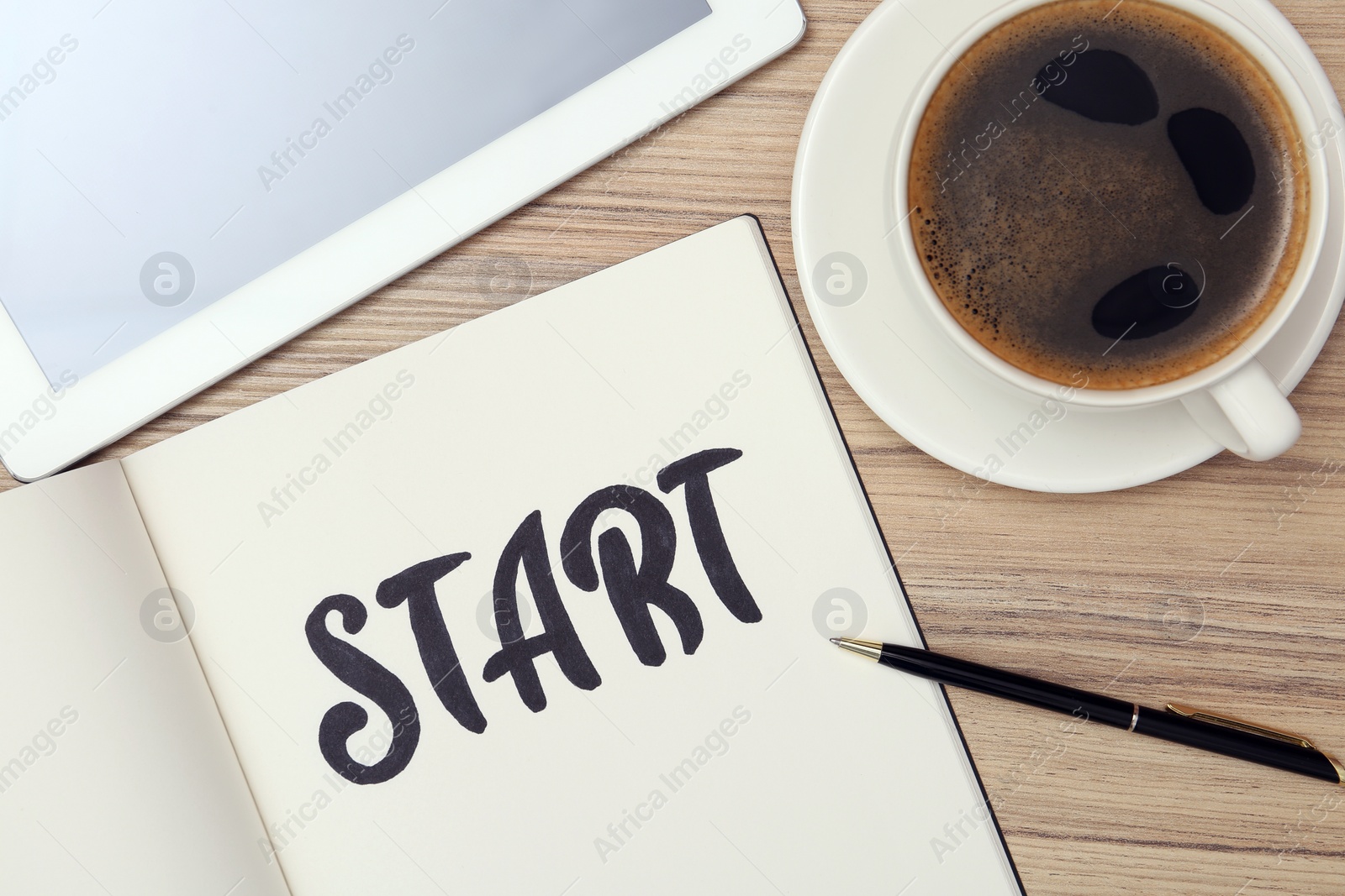 Photo of Notebook with word Start, cup of coffee and tablet on wooden table, flat lay