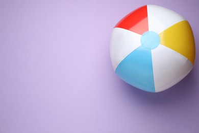 Photo of Colorful beach ball on violet background, top view. Space for text