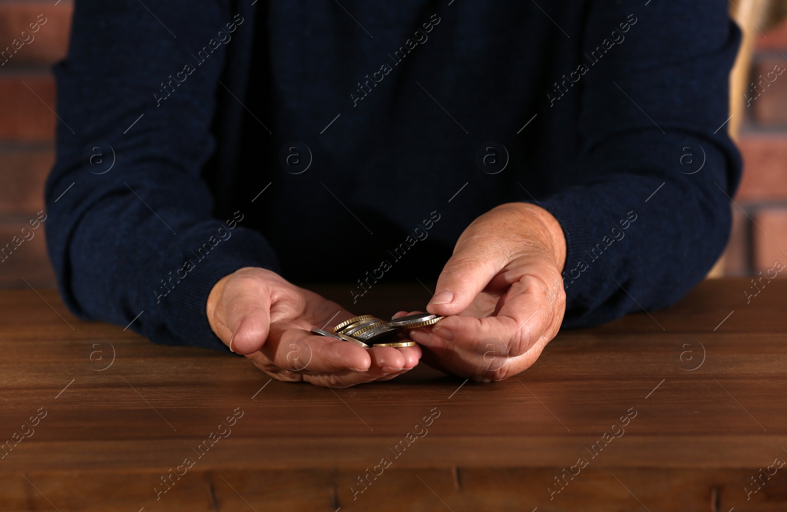 Photo of Poor elderly woman counting coins at table, focus on hands