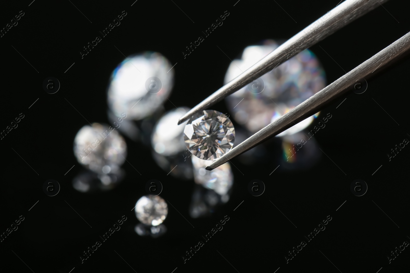 Photo of Tweezers with beautiful shiny diamond against black background, closeup