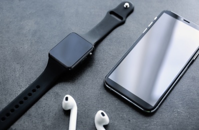 Photo of Stylish smart watch, phone and earphones on grey table