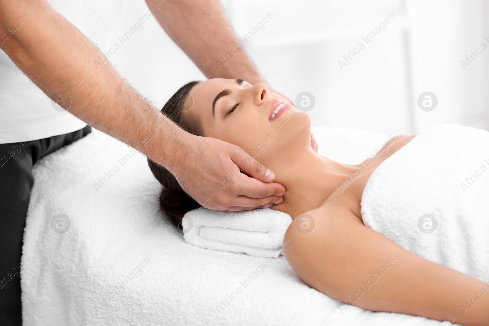 Photo of Relaxed woman receiving neck massage in wellness center