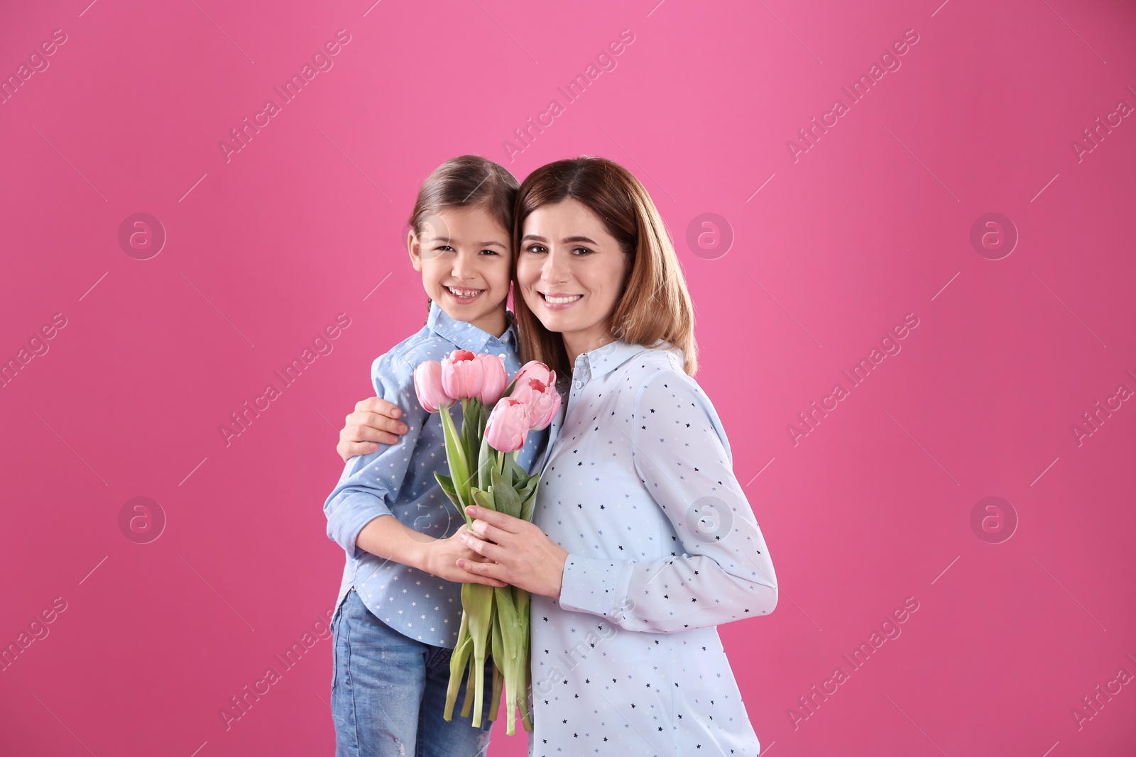 Photo of Happy mother and daughter with flowers on color background. International Women's Day