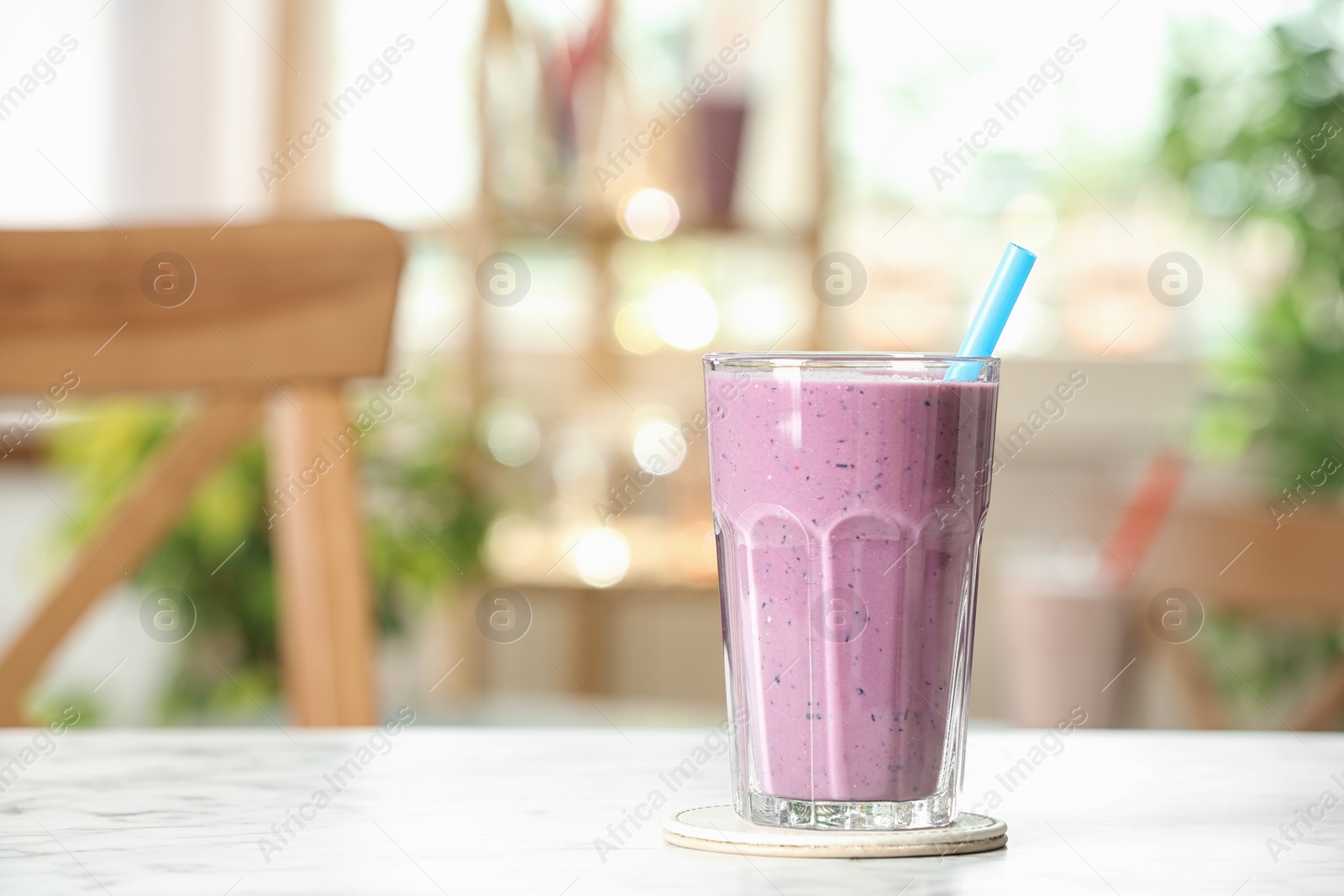 Photo of Tasty milk shake on white marble table indoors. Space for text