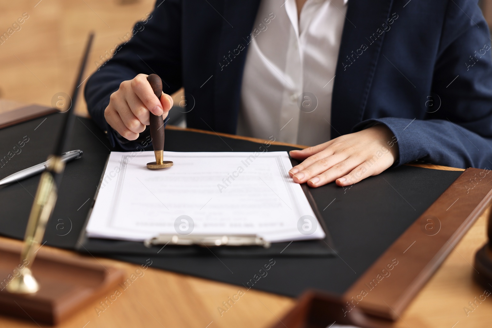 Photo of Notary sealing document at table in office, closeup