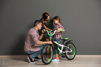 Photo of Portrait of parents and their daughter with bicycle near color wall