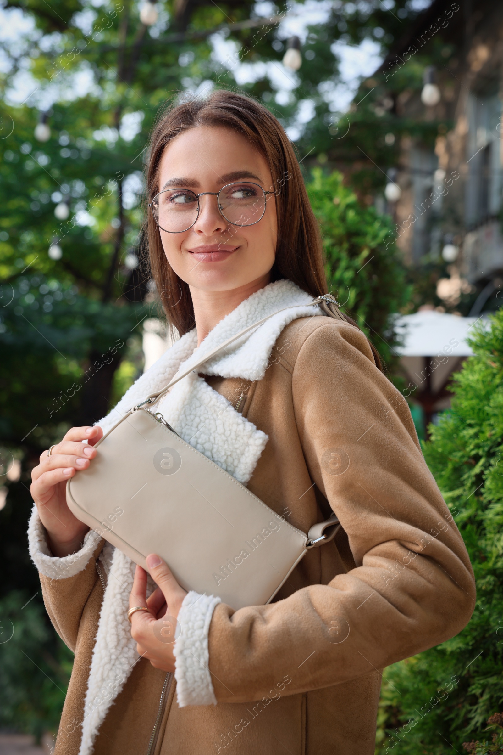 Photo of Fashionable young woman with stylish bag on city street