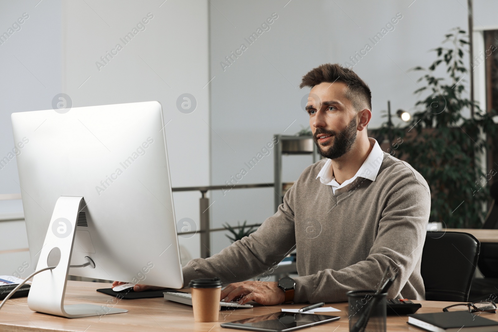 Photo of Man working on computer at table in office