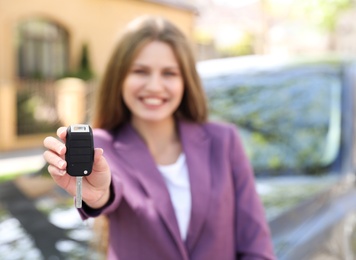 Young woman with key near new car outdoors, focus on hand