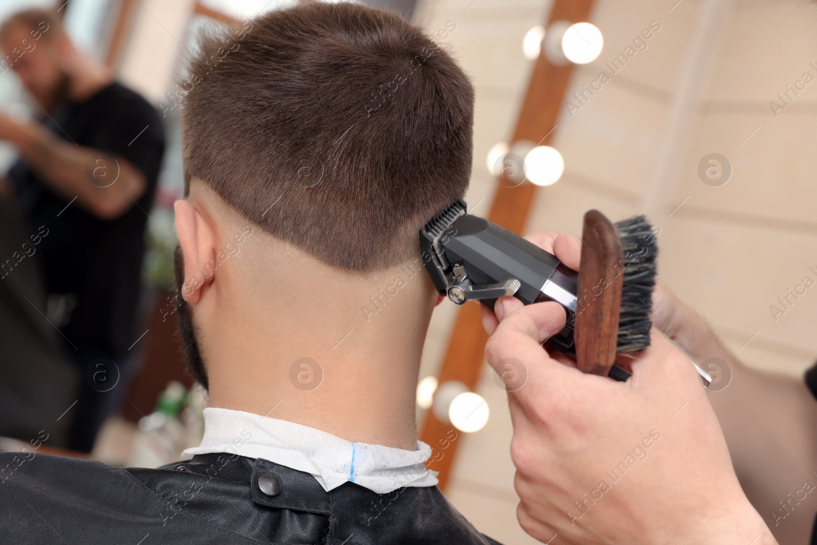 Photo of Professional hairdresser working with client in barbershop, closeup