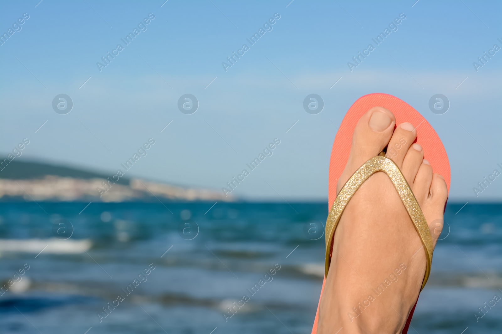 Photo of Woman wearing stylish flip flop near sea, closeup. Space for text