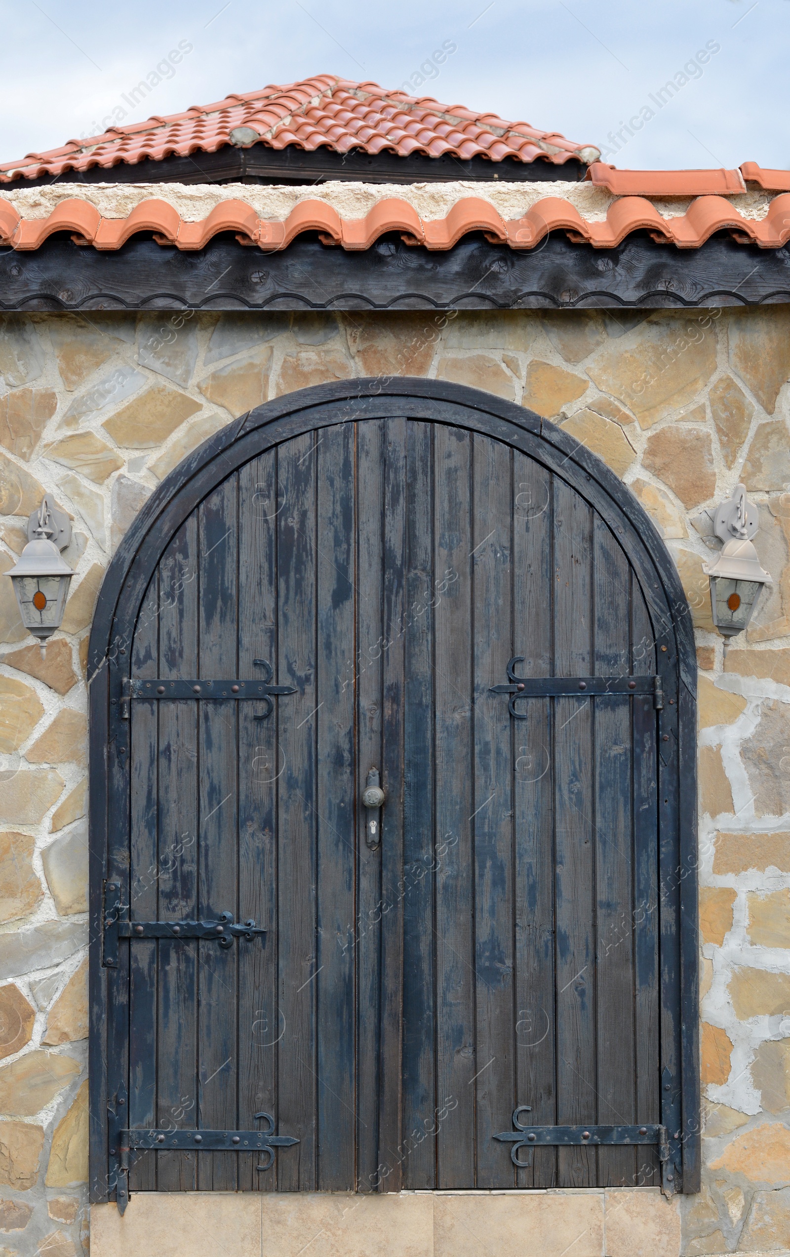 Photo of Entrance of building with beautiful arched wooden door in stone wall outdoors