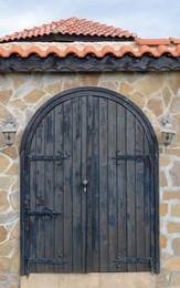 Entrance of building with beautiful arched wooden door in stone wall outdoors