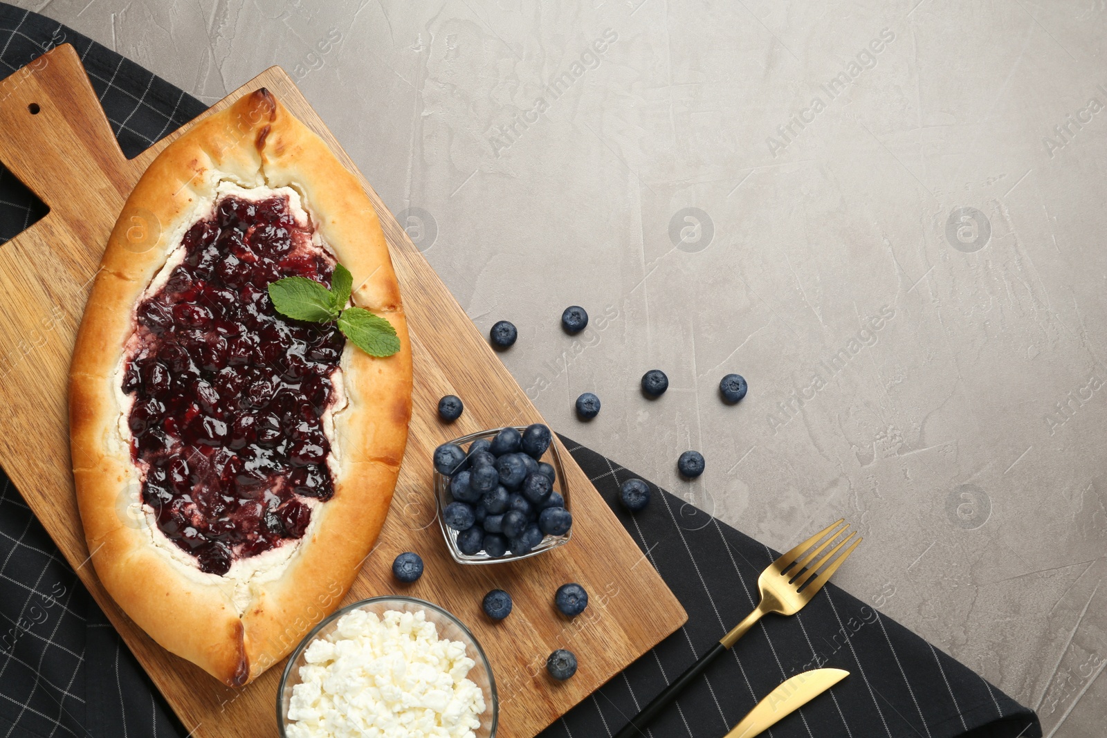 Photo of Delicious sweet cottage cheese pastry with cherry jam served on grey table, flat lay. Space for text