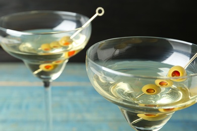 Photo of Glasses of Classic Dry Martini with olives on wooden table, closeup