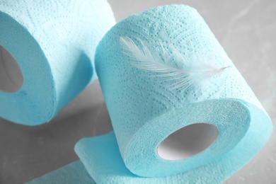 Toilet paper rolls with feather on grey background
